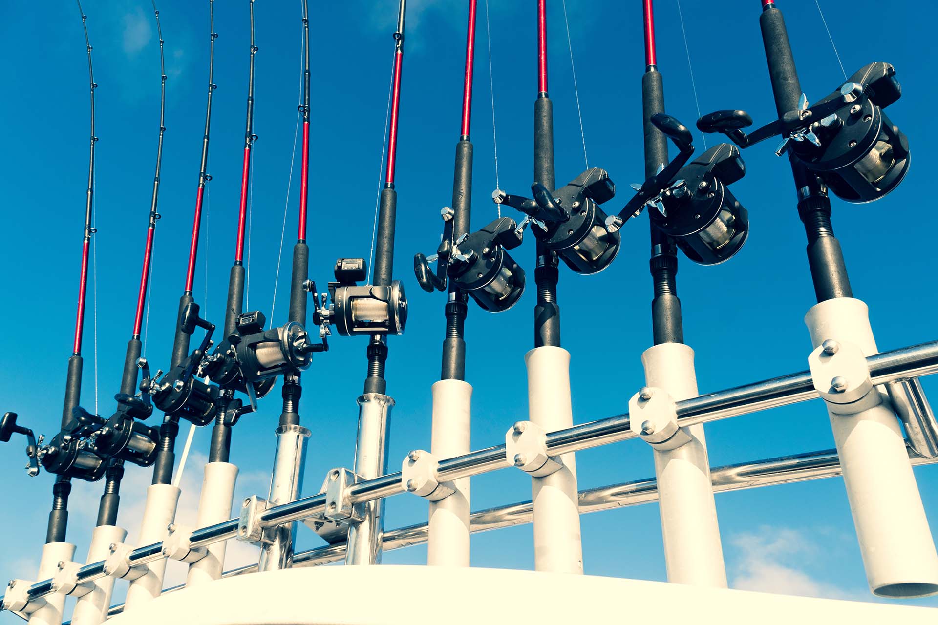 Fishing trolling boat rods in rod holder. Big game fishing. Fishing reels and rods pattern on boat. Sea fishing rods and reels in a row