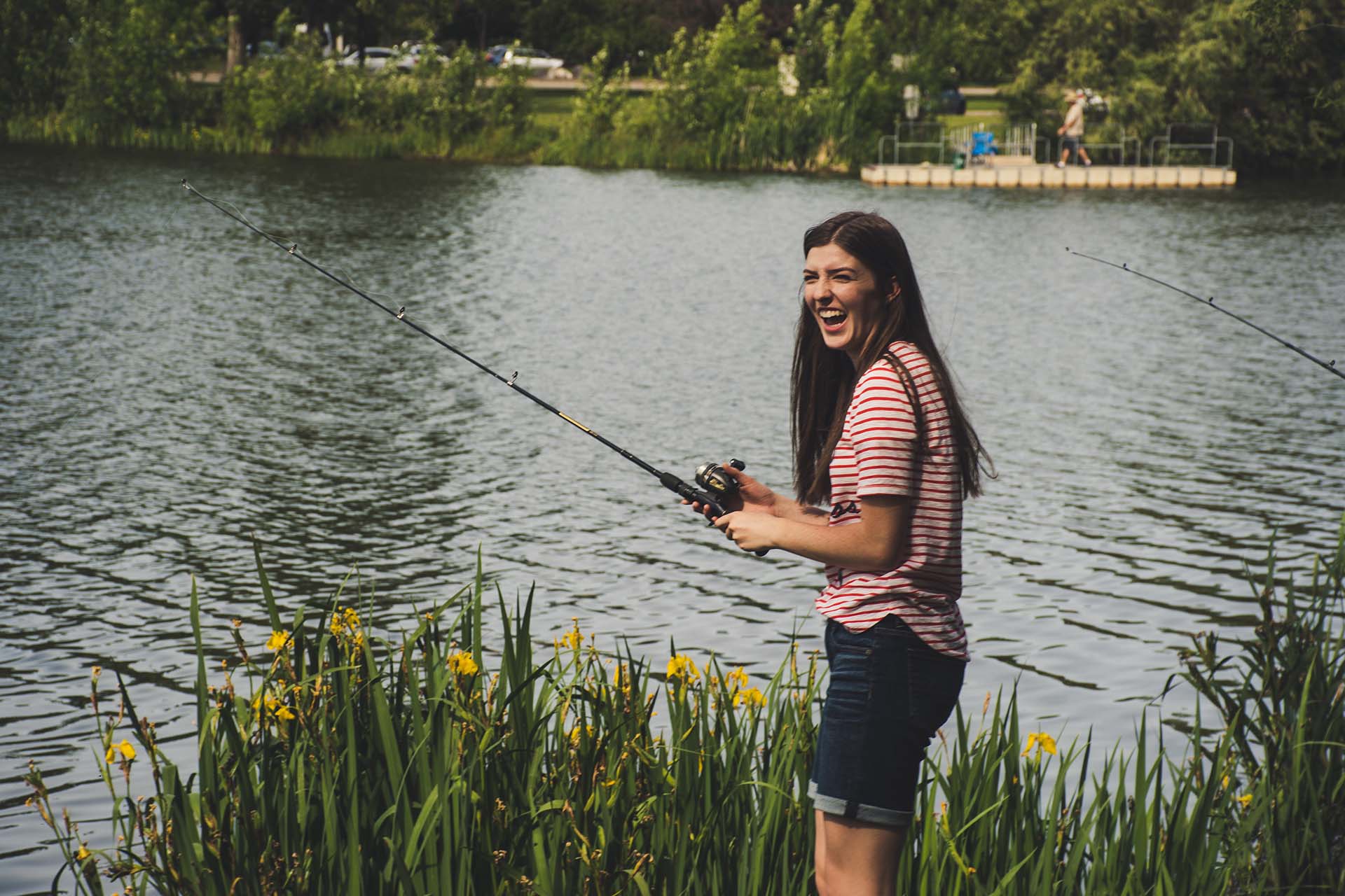 A girl holding a fishing rod by the lake