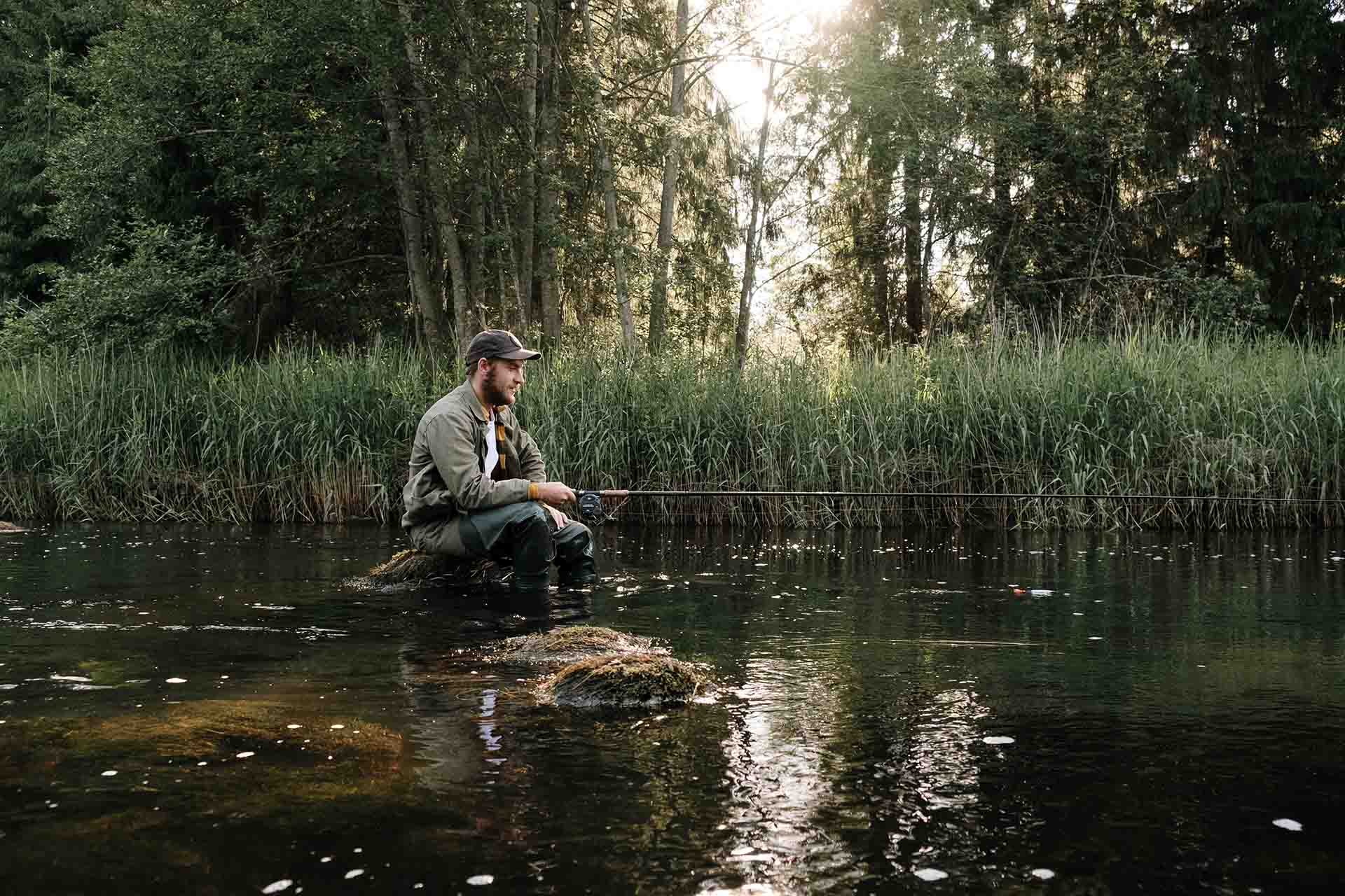 A man sitting in a stream while fishing