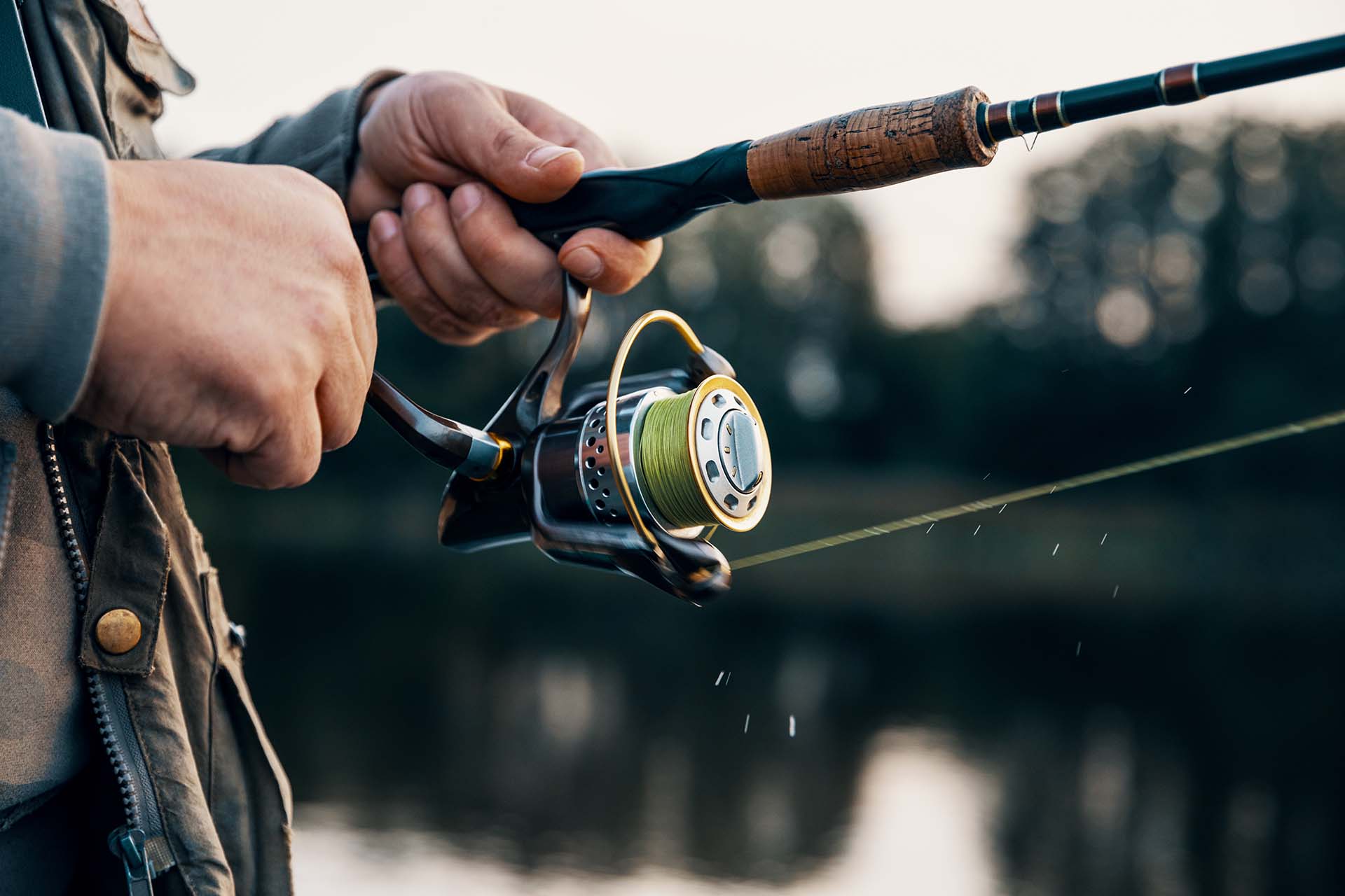 Fishing rod with a spinning reel in the hands of a fisherman. Fishing background.