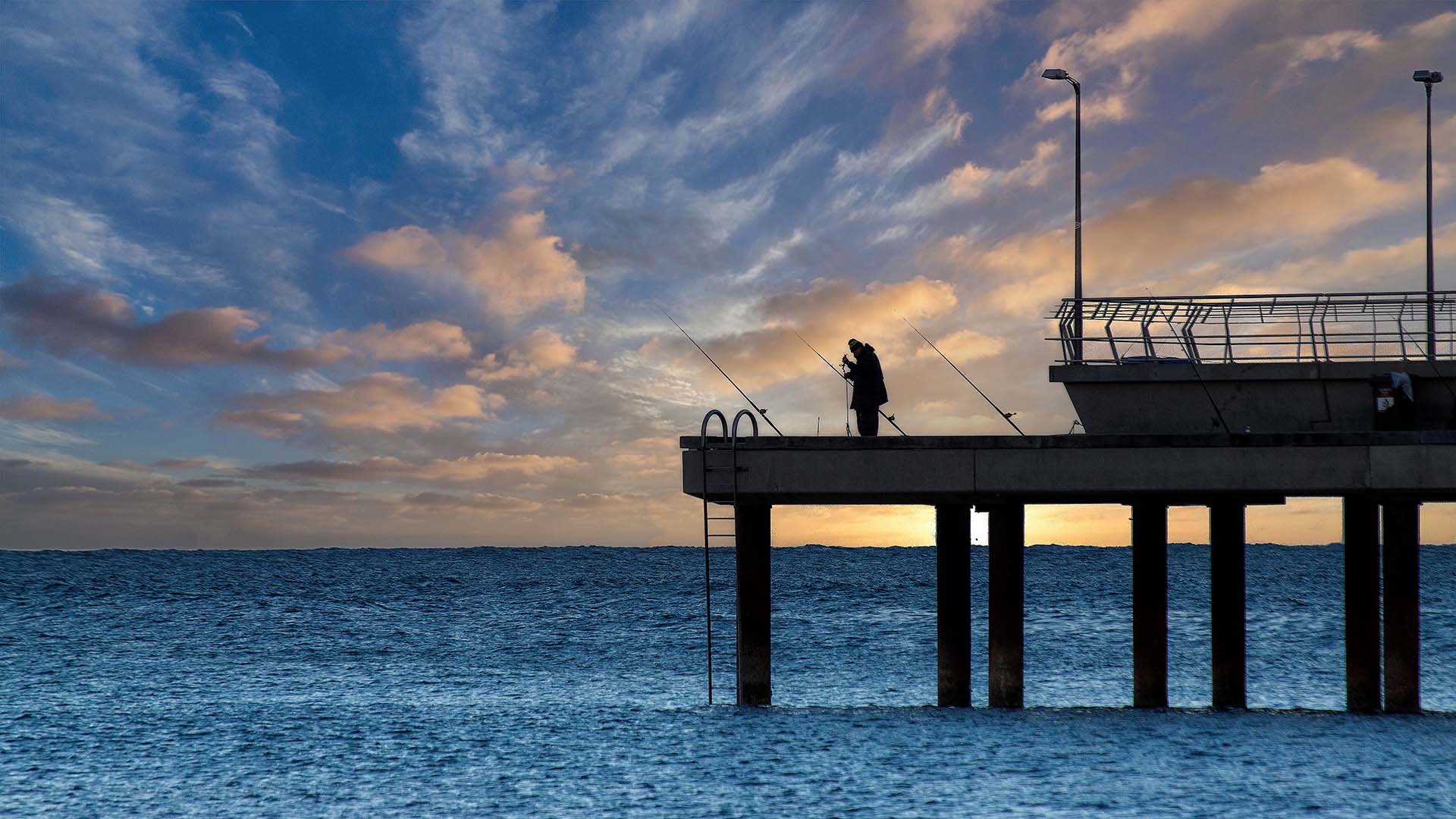 Man fishing at the pier during sunset
