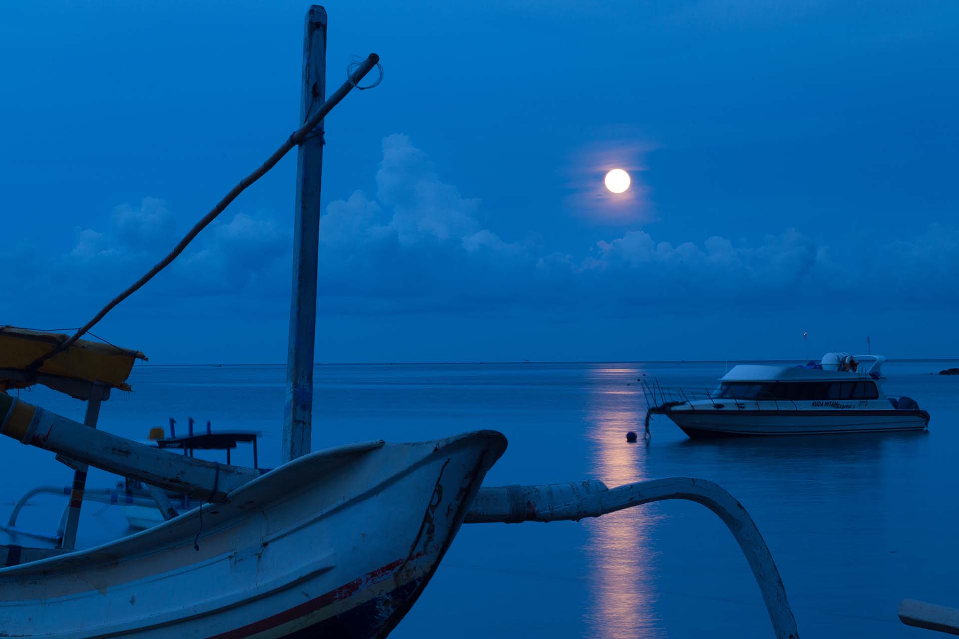 Boats at the shore with a full moon in the sky