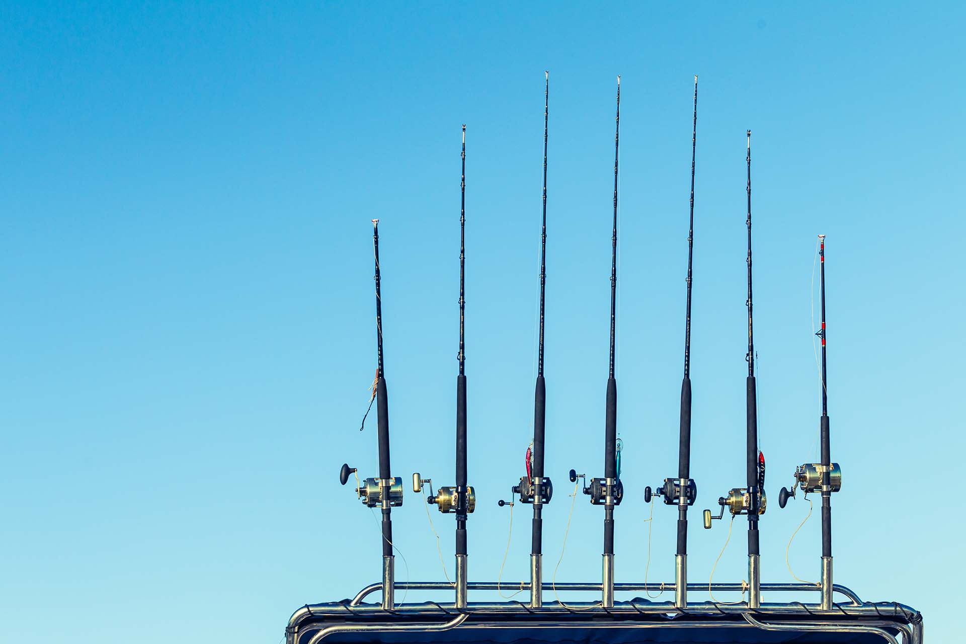 Fishing rods on a boat against morning blue sky 