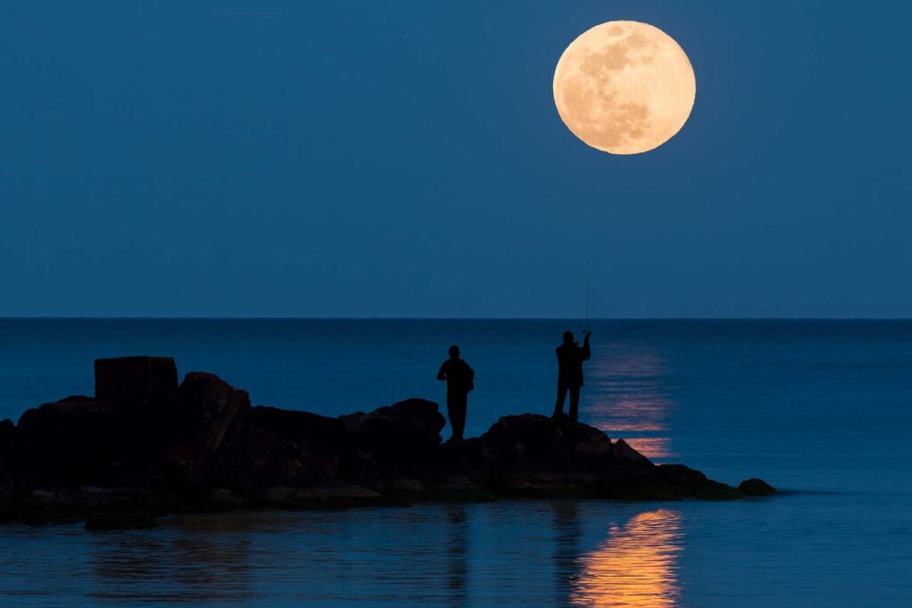 Two anglers are fishing in the Mediterranean and in the background