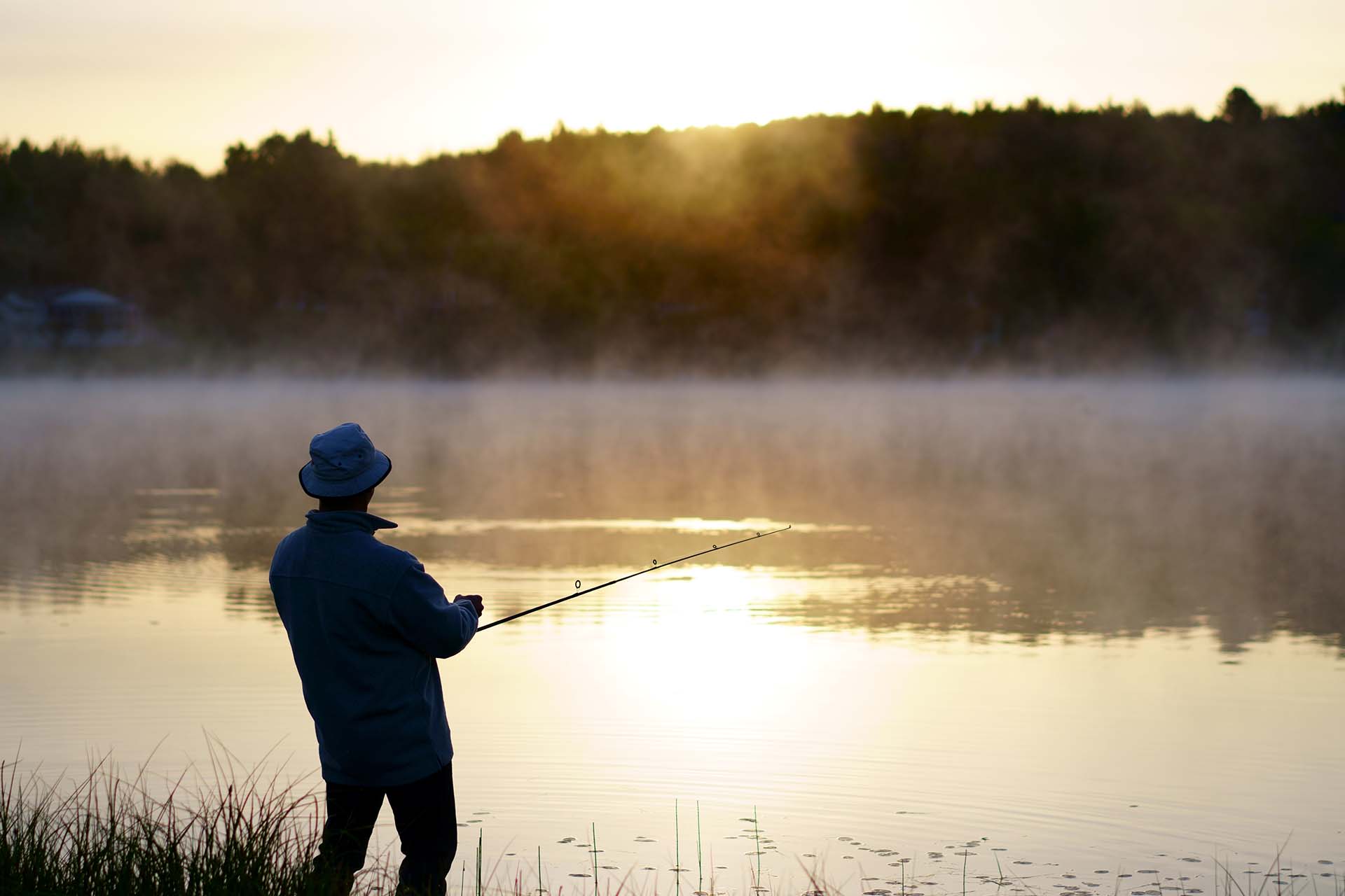 fisherman at the lake with fog, fishing early morning just before sunrise