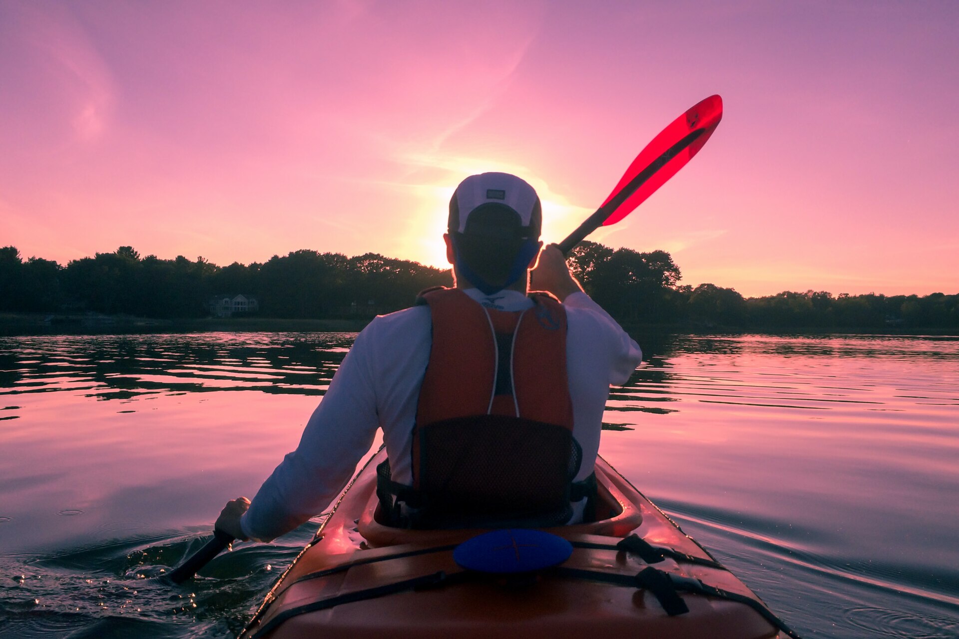 Man kayaking in a river during sunset