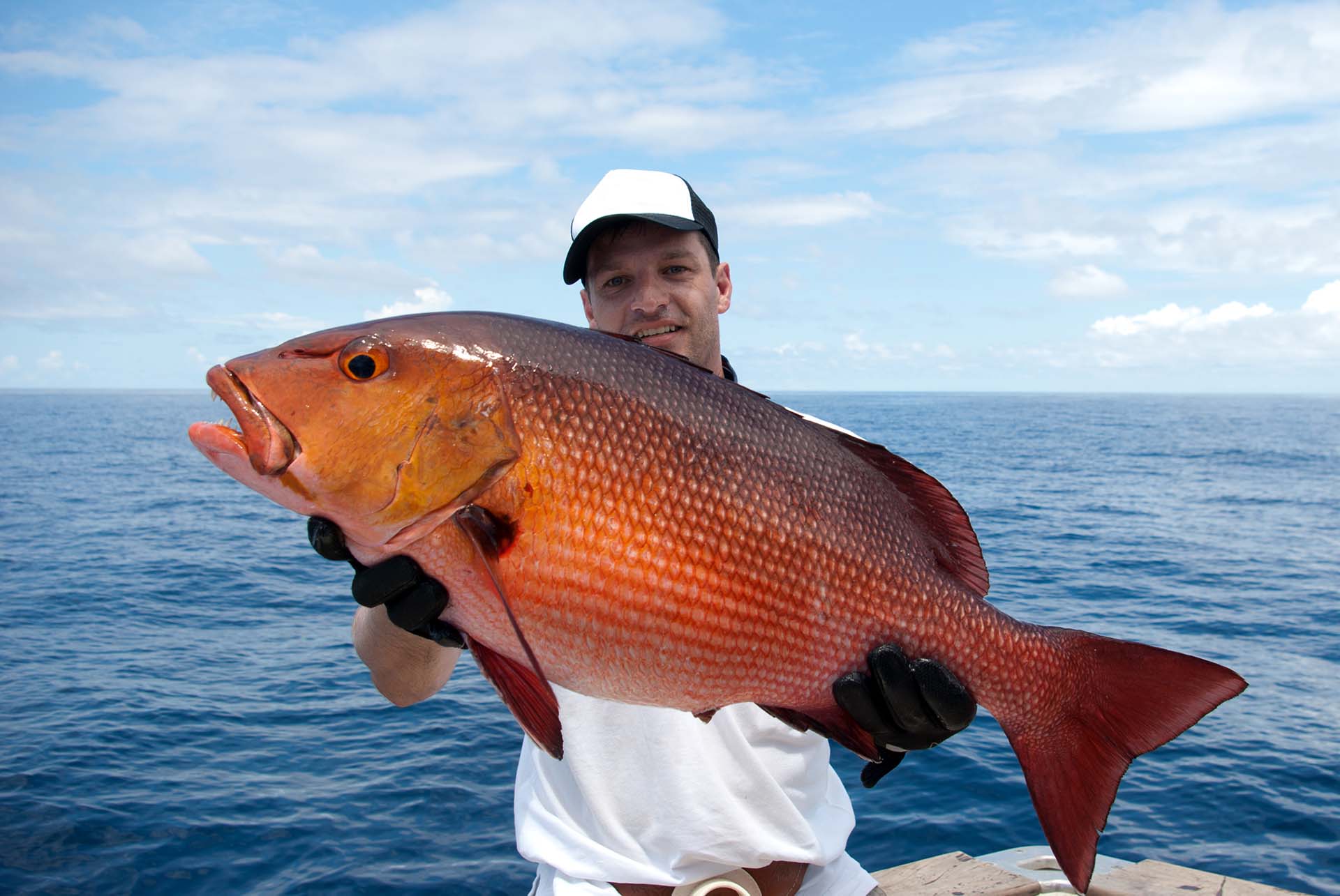 A happy fisherman holding a red snapper