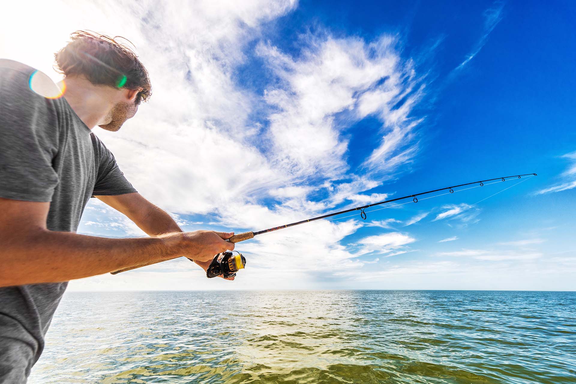 Man fishing in the sea from boat casting bait throwing line