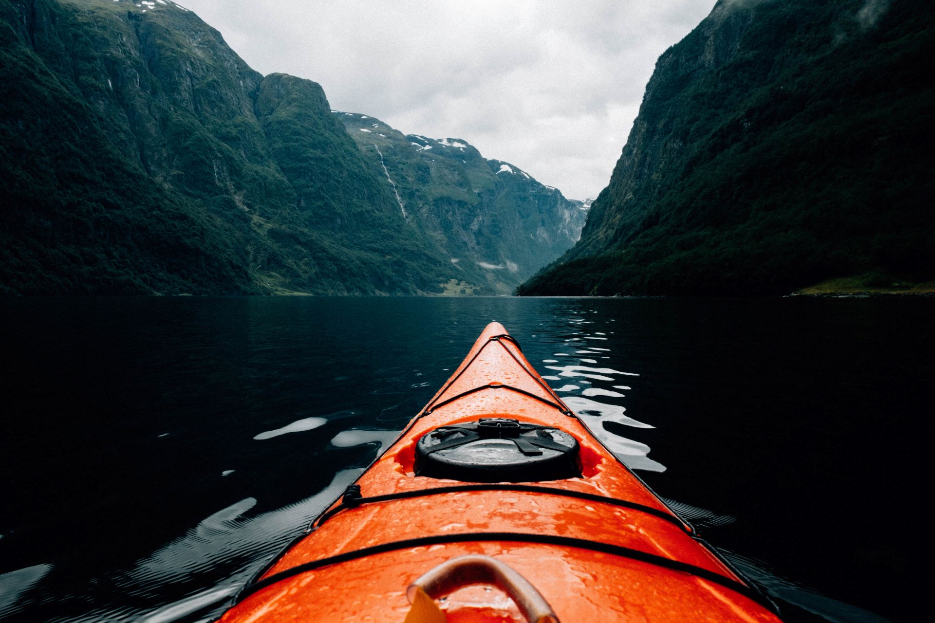 An orange kayak on the water between mountains