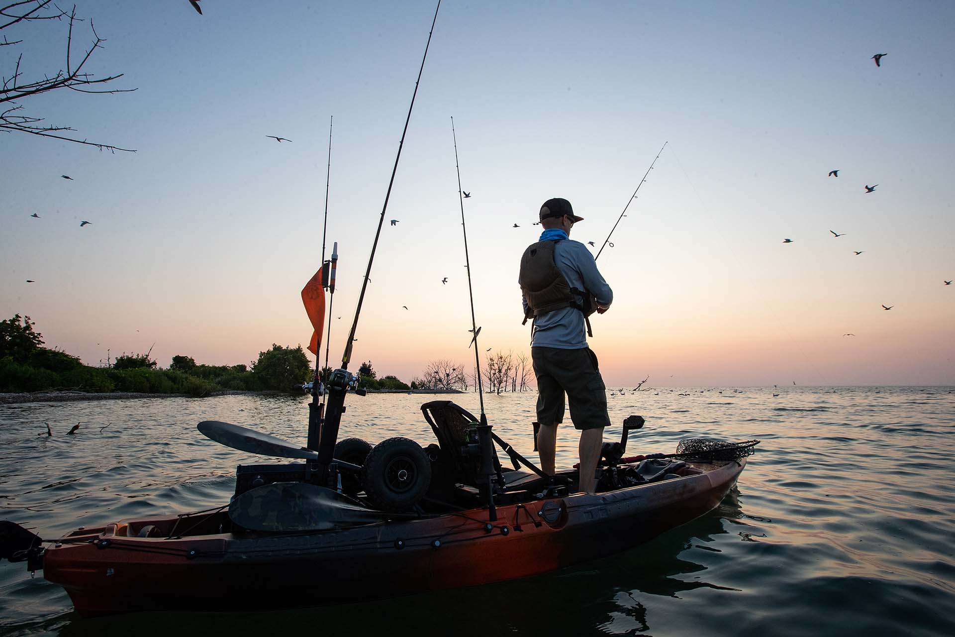 Young man kayak fishing during sunrise