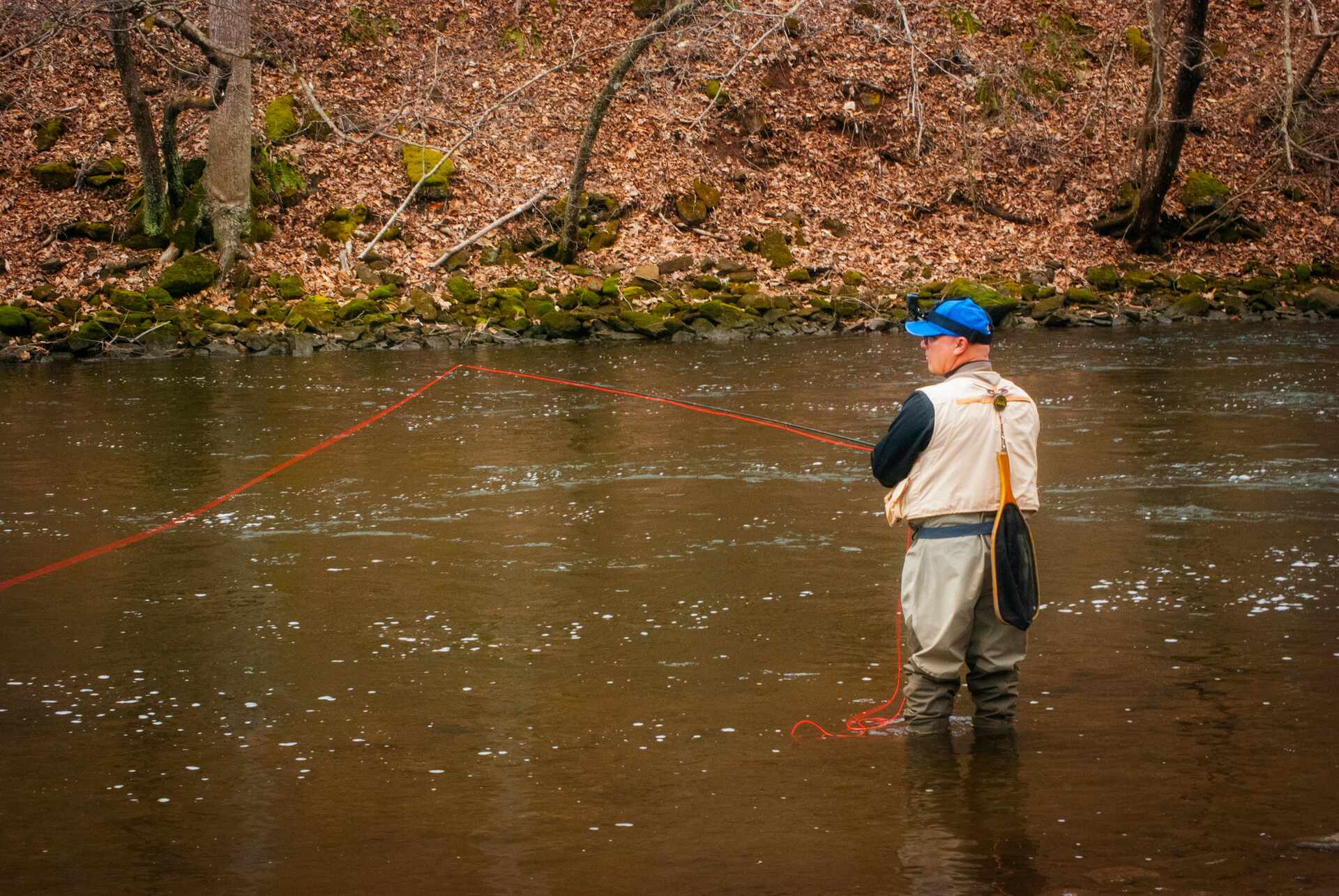Man fly fishing in a small stream during fall
