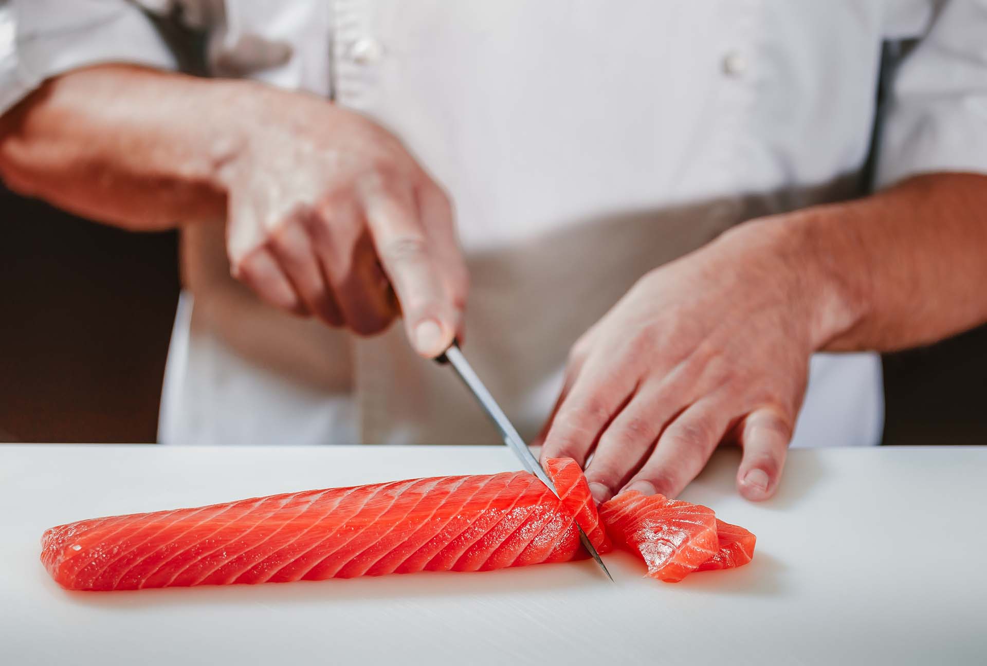 Cutting fresh red salmon fish with a sharp knife