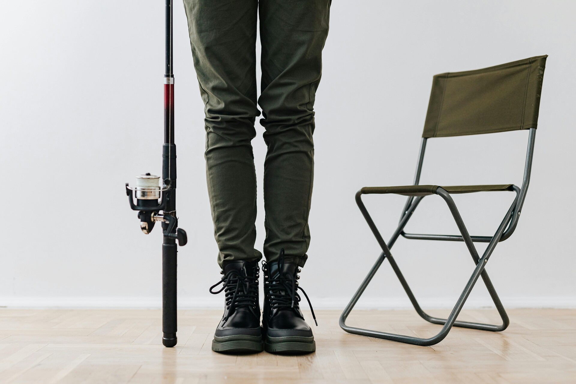 A person wearing boots and holding a fishing rod standing