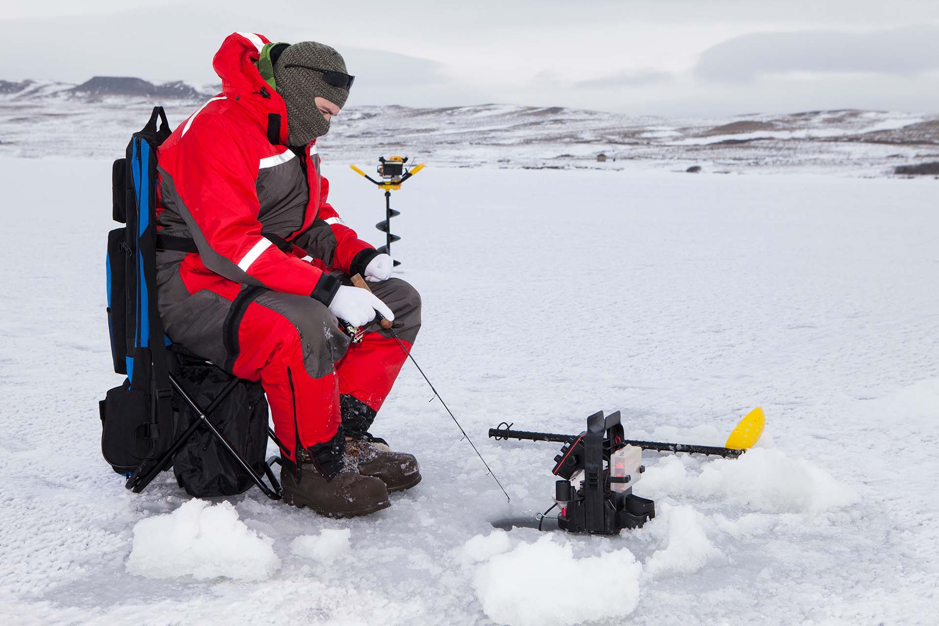 Man ice fishing on a cold winter day.