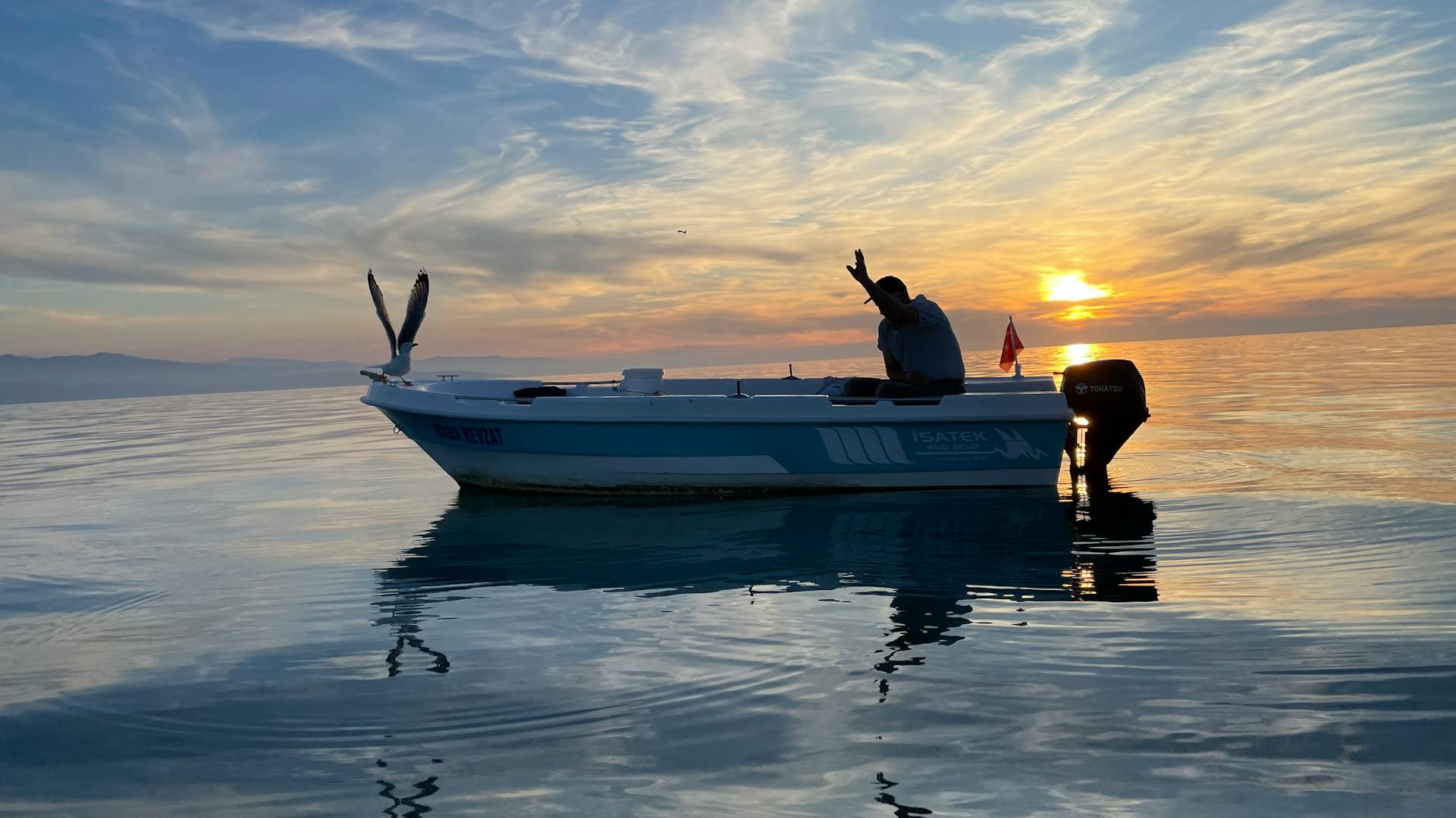 A man on a boat at sea at sunset